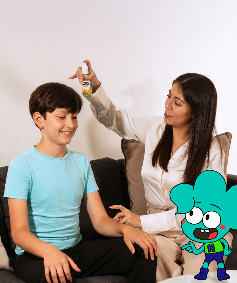 Una madre aplica Herklin Spray Prevención en el cabello de su hijo, sentados en el sofá.