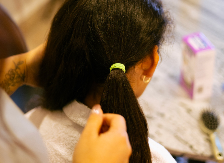 Una mano separa el cabello en secciones y lo sujeta con una liga.