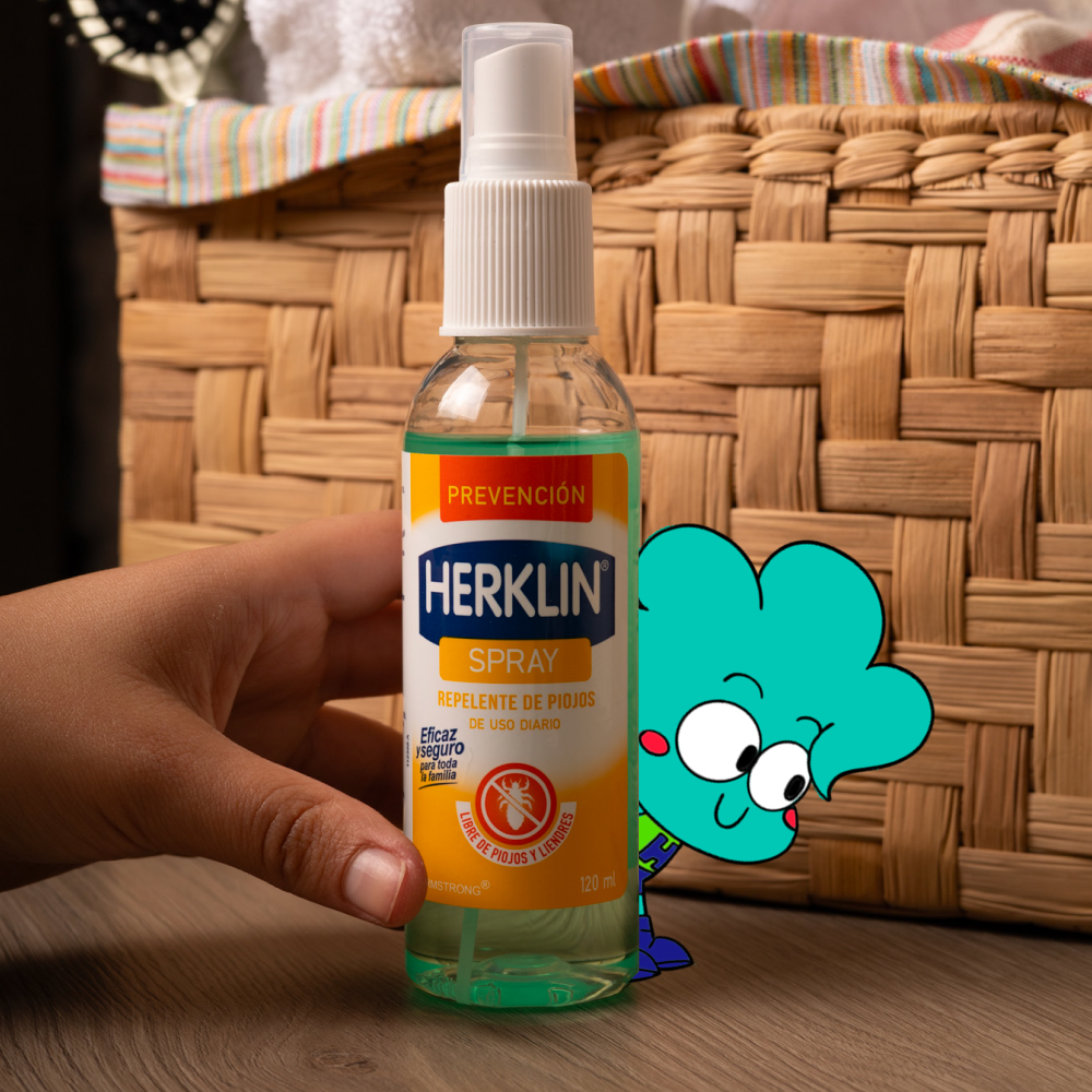 Una mano sostiene el frasco de Herklin Spray Prevención sobre una mesa.